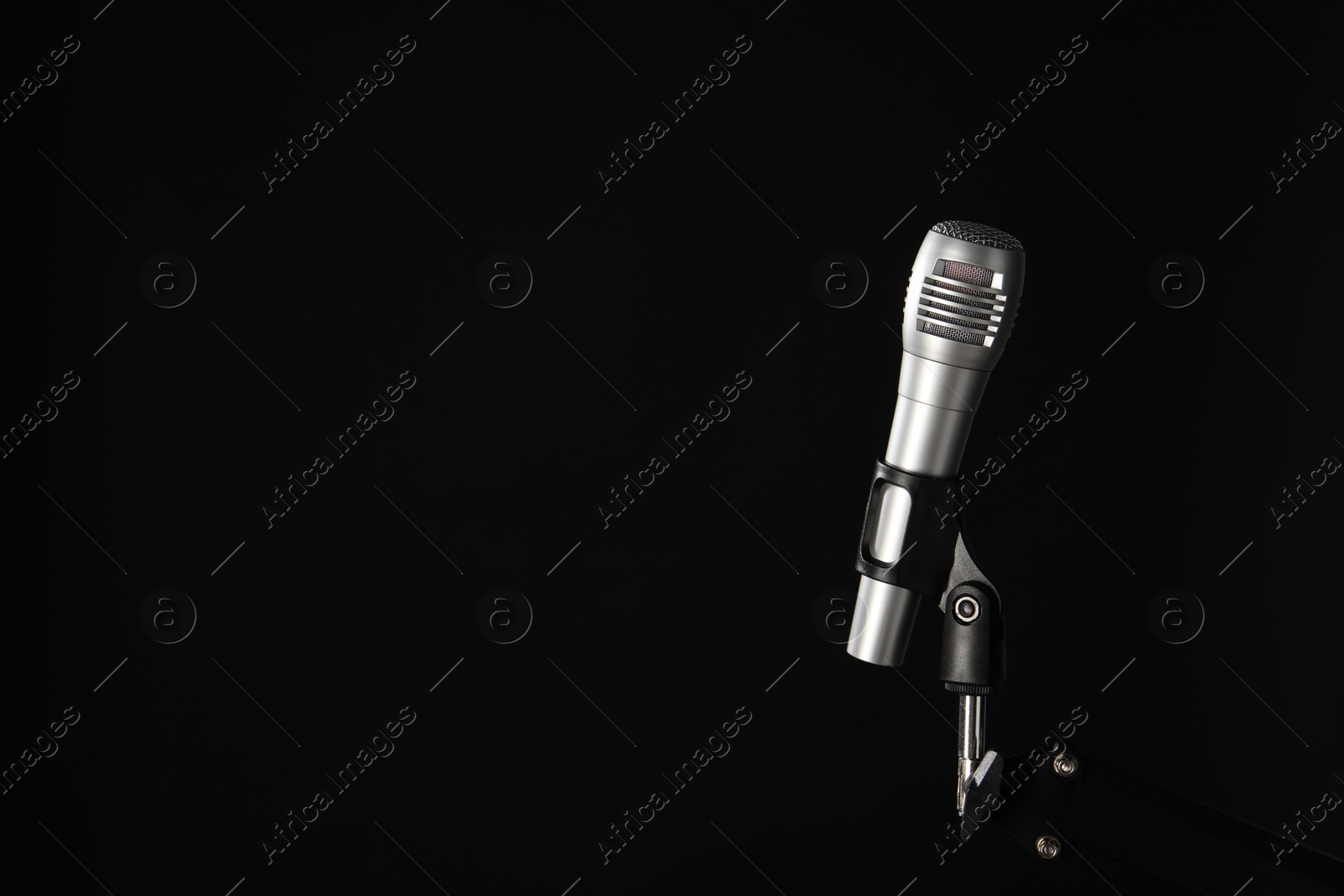 Photo of Stand with microphone on black background, space for text. Sound recording and reinforcement
