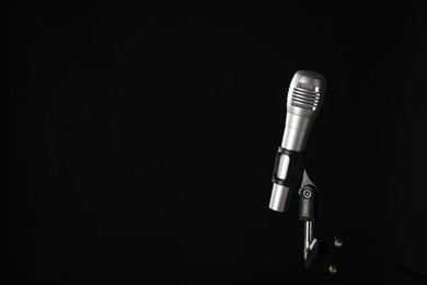 Photo of Stand with microphone on black background, space for text. Sound recording and reinforcement