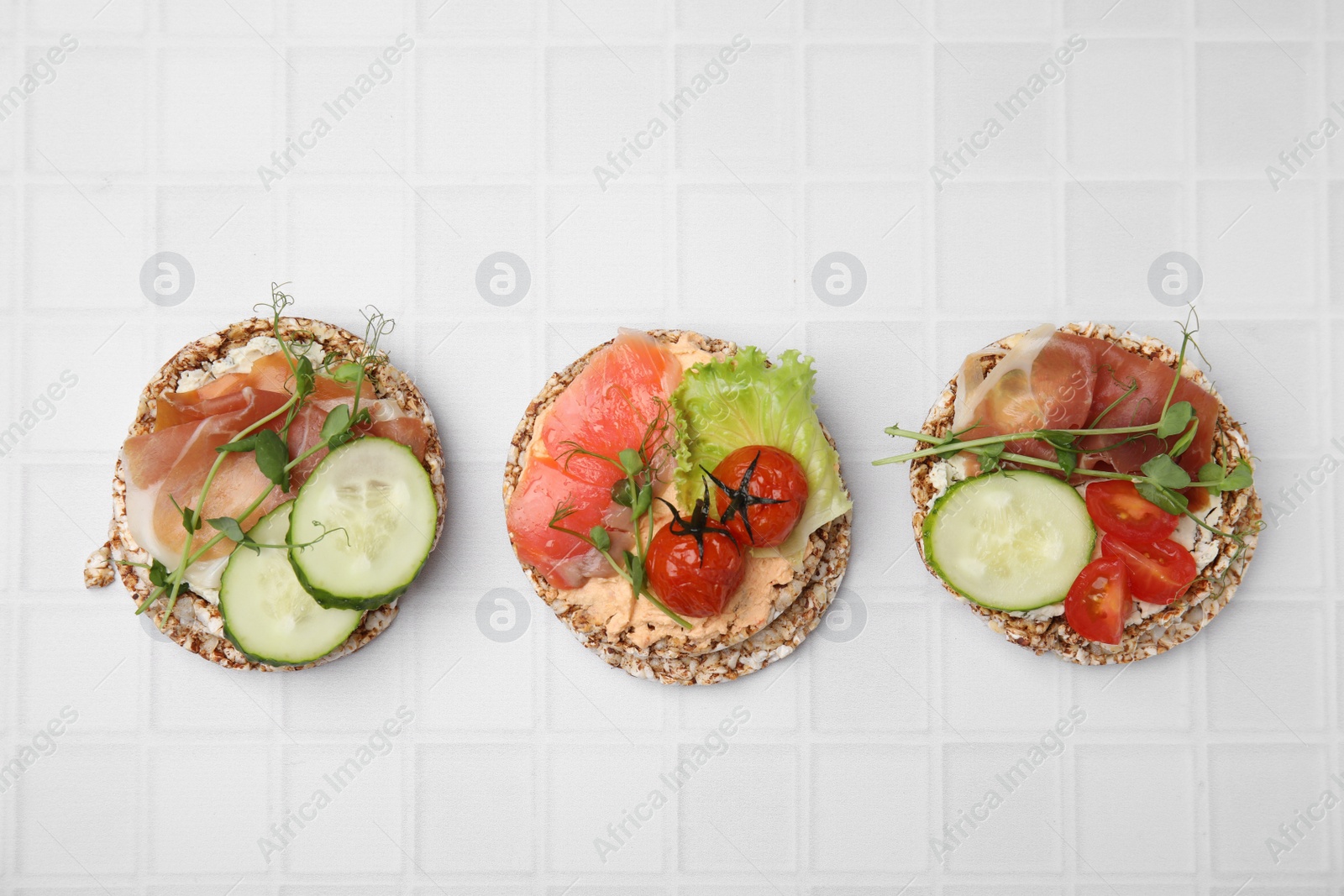 Photo of Set of crunchy buckwheat cakes with different ingredients on white background, flat lay