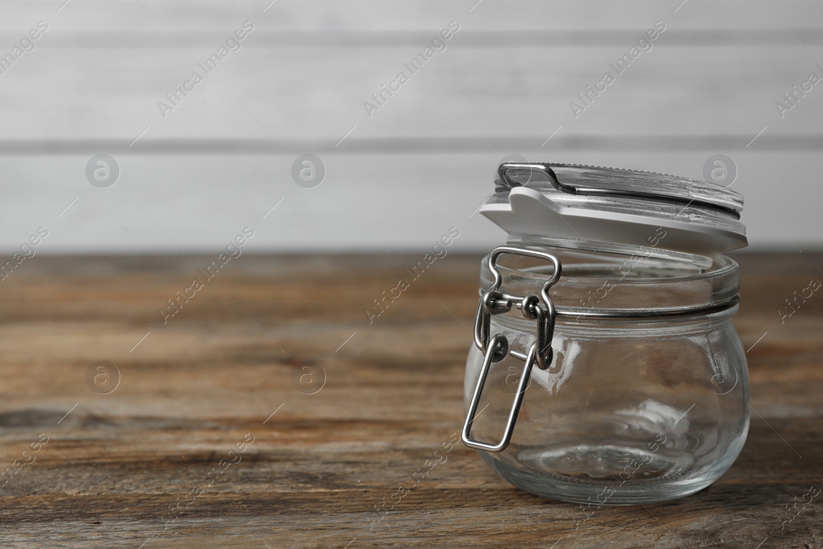 Photo of Empty glass jar on wooden table, space for text