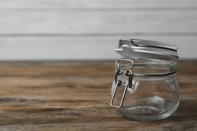 Empty glass jar on wooden table, space for text