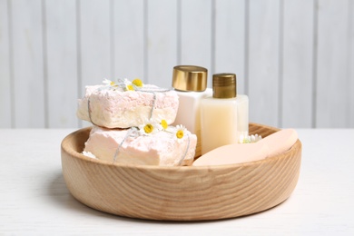 Composition with chamomile flowers and cosmetic products on white table