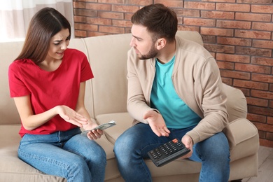 Photo of Unhappy young couple with money at home. Financial problems