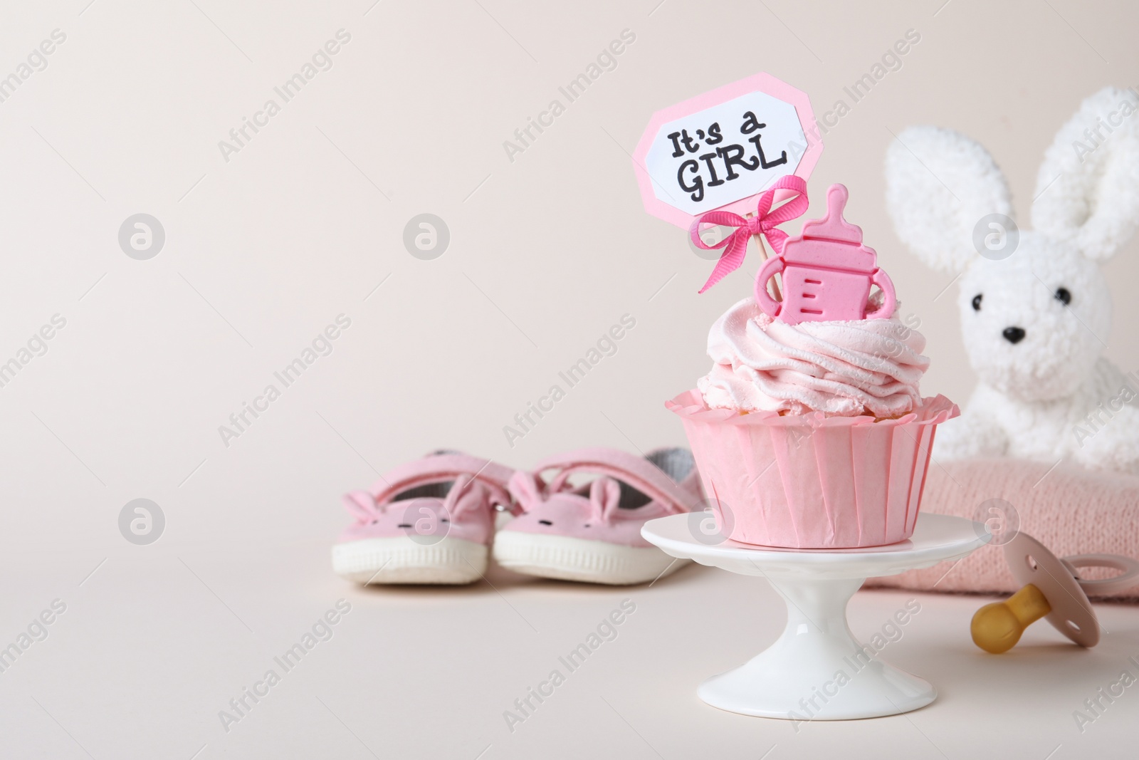 Photo of Beautifully decorated baby shower cupcake with cream and girl topper on light background. Space for text