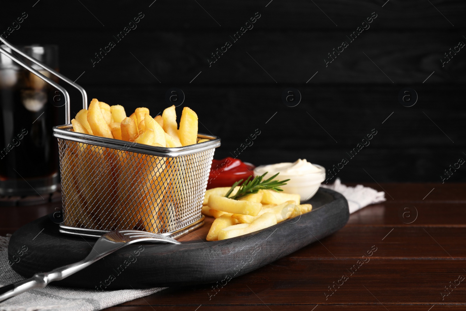 Photo of Tasty french fries and dip sauces served on wooden table, space for text