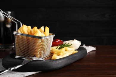 Tasty french fries and dip sauces served on wooden table, space for text