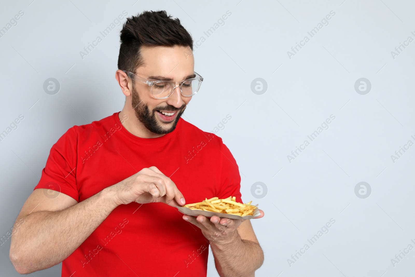 Photo of Man with French fries on grey background, space for text