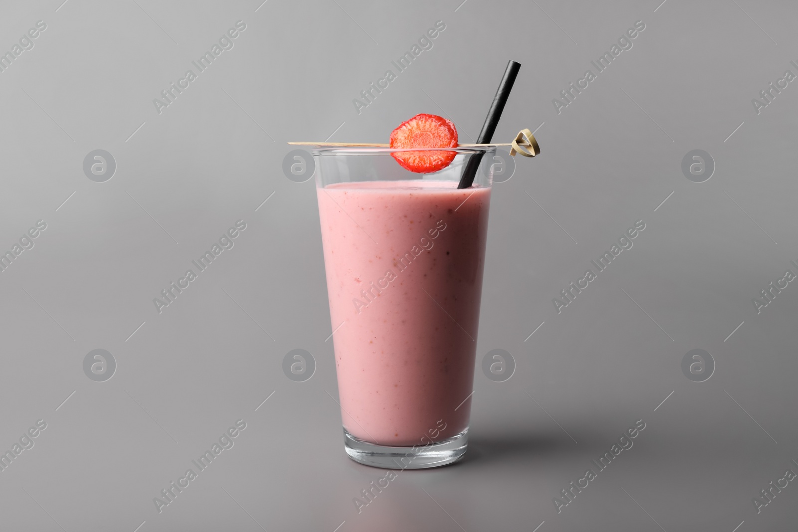 Photo of Glass with delicious fresh berry smoothie on grey background