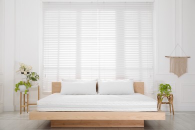 Photo of Wooden bed with soft white mattress and pillows in cozy room interior