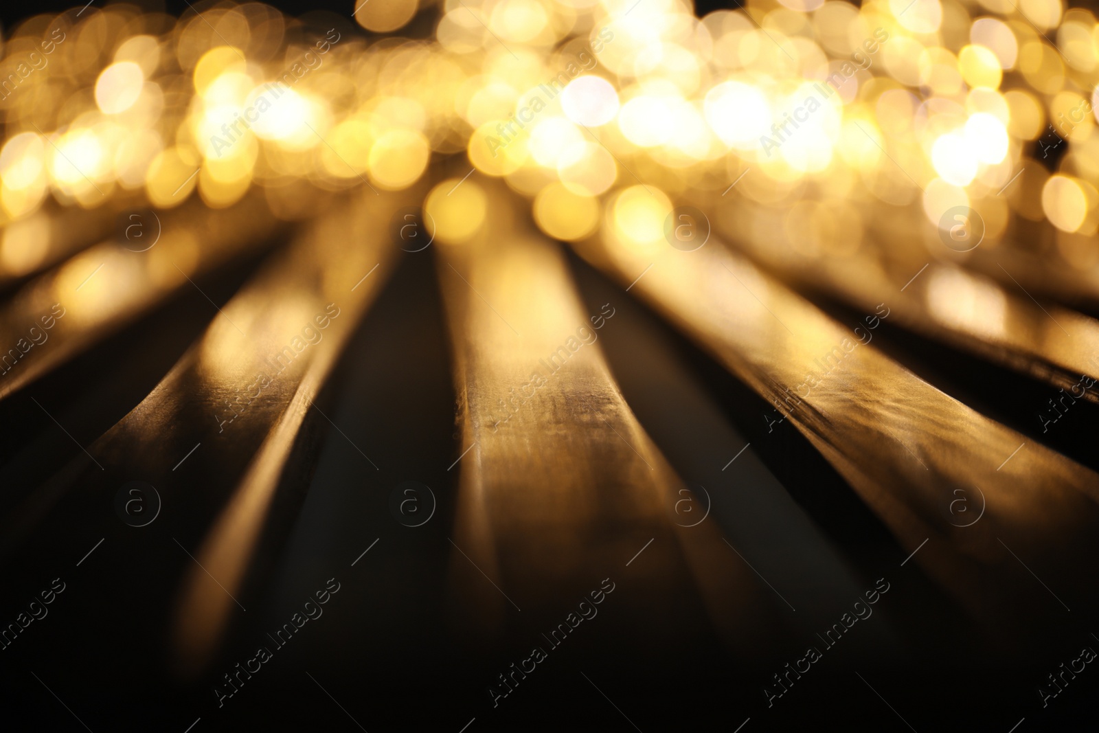 Photo of Golden blurred lights and planks on dark background. Bokeh effect