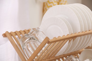 Drying rack with clean dishes on light background, closeup