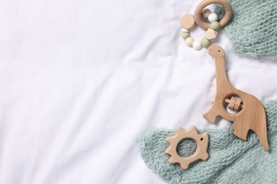 Photo of Baby accessories. Rattles, teether and child's clothes on white fabric, flat lay. Space for text