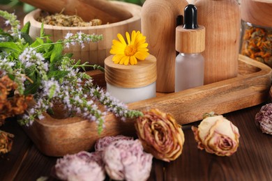 Photo of Jar, bottles of essential oils and different herbs on wooden table