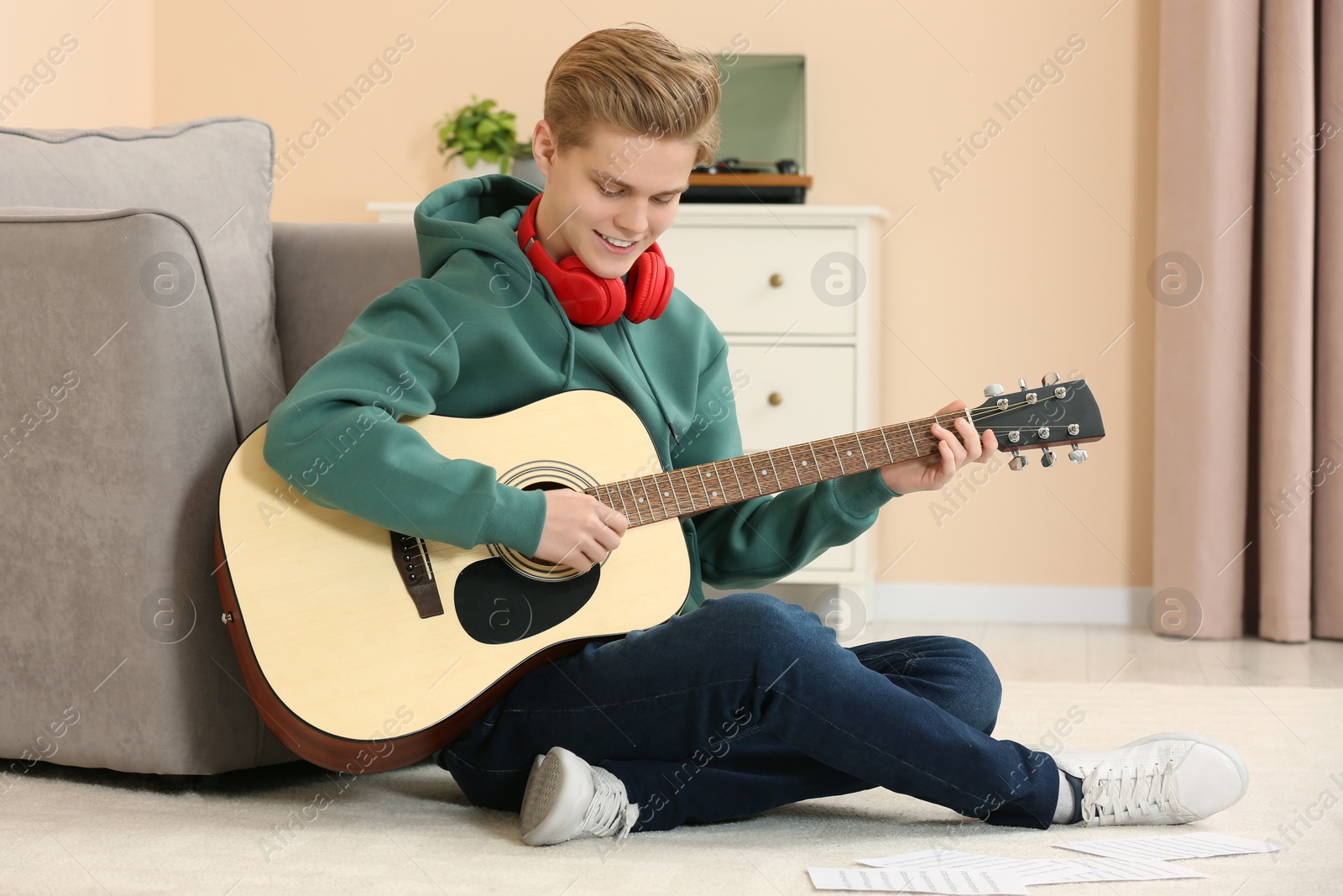 Photo of Teenage boy playing acoustic guitar in room