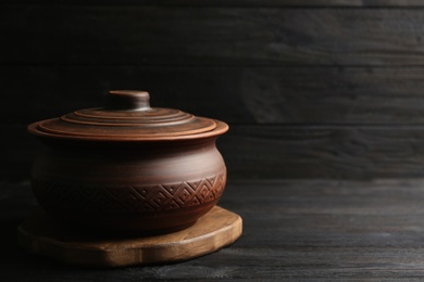 Clay pot on black wooden table, space for text. Handmade utensil
