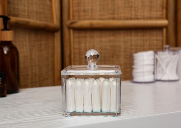 Photo of Glass holder with many tampons on white table. Menstrual hygienic product