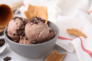 Tasty ice cream with chocolate chunks and pieces of waffle cone on table, closeup