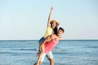 Happy young couple having fun at beach on sunny day