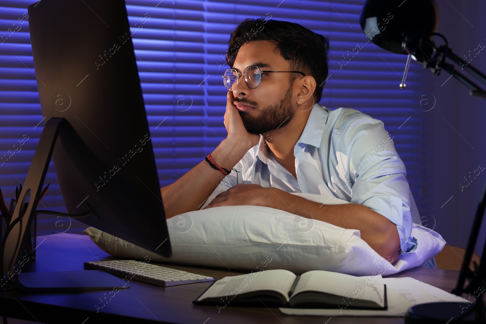 Photo of Tired young man working late in office