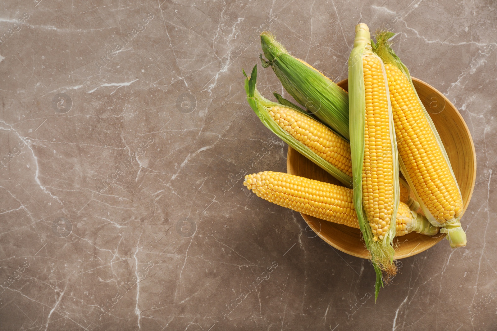 Photo of Bowl with tasty sweet corn cobs on table, top view