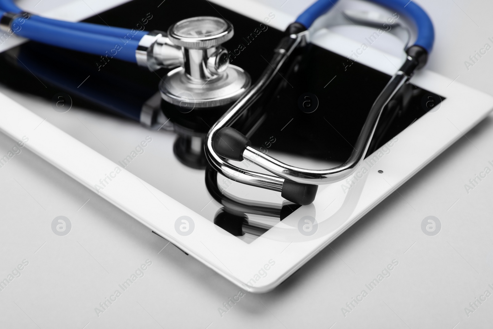 Photo of Medical stethoscope and tablet on white background, closeup