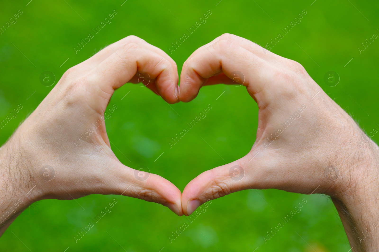 Photo of Man making heart with hands outdoors, closeup