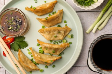 Photo of Delicious gyoza (asian dumplings) served on light tiled table, flat lay