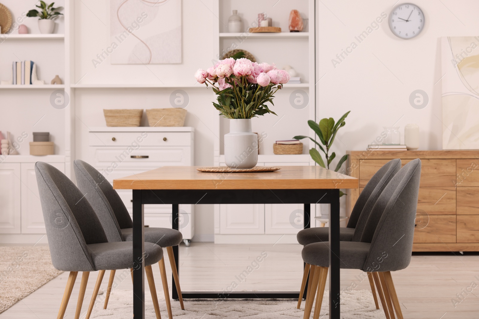 Photo of Table, chairs and vase with peonies in stylish dining room