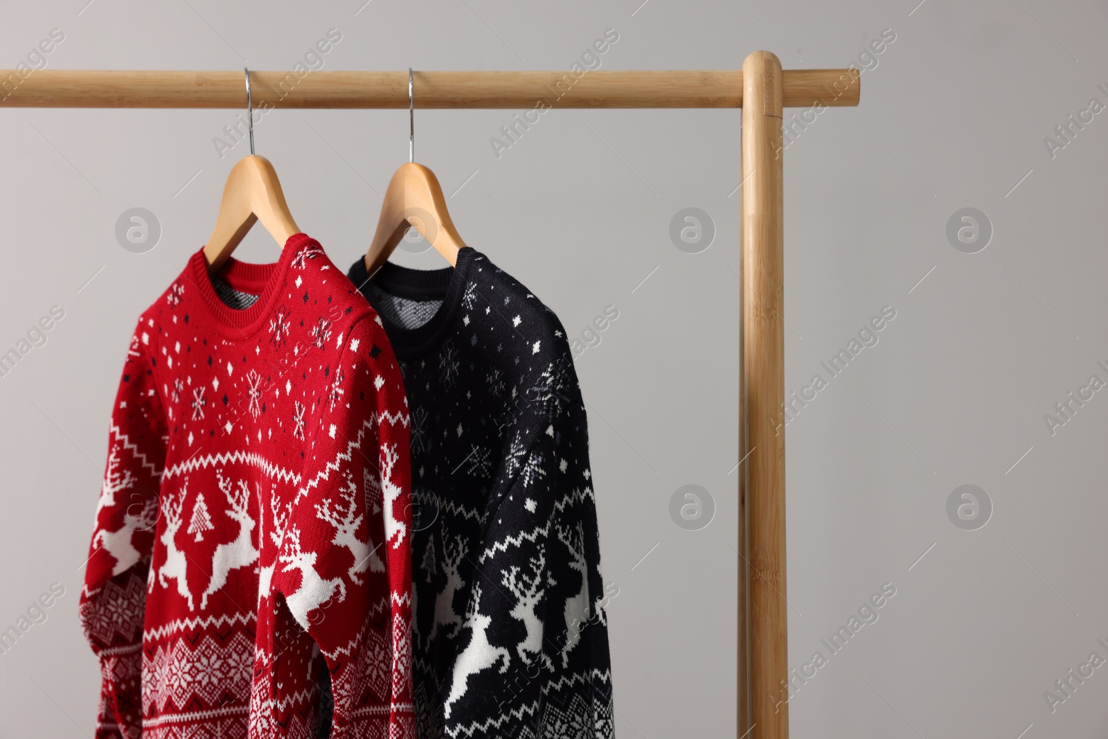 Photo of Rack with Christmas sweaters on light background