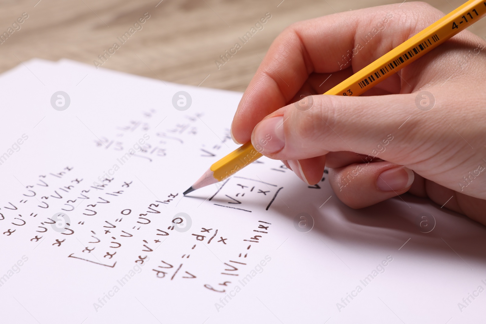 Photo of Student writing different mathematical formulas on paper, closeup