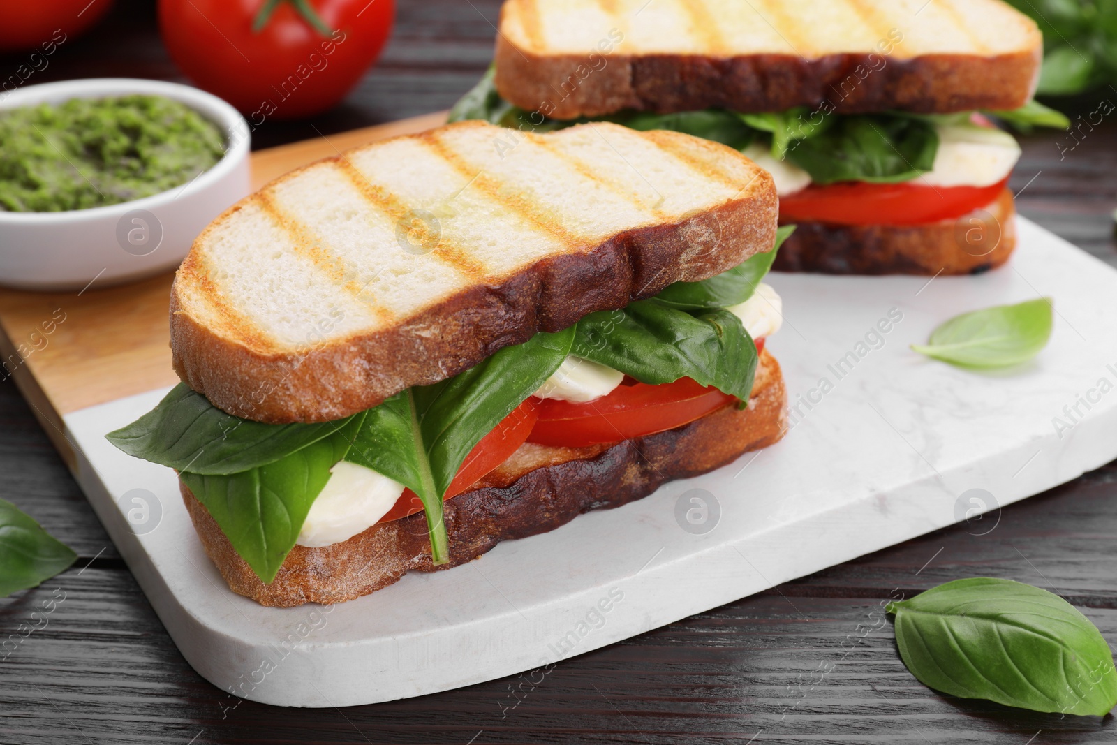 Photo of Delicious Caprese sandwiches with mozzarella, tomatoes and basil on wooden table, closeup