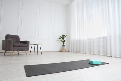 Exercise mat and yoga block indoors. Space for text
