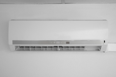 Modern air conditioner on white wall indoors