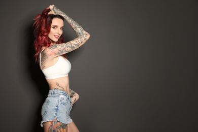 Photo of Beautiful woman with tattoos on body against black background. Space for text
