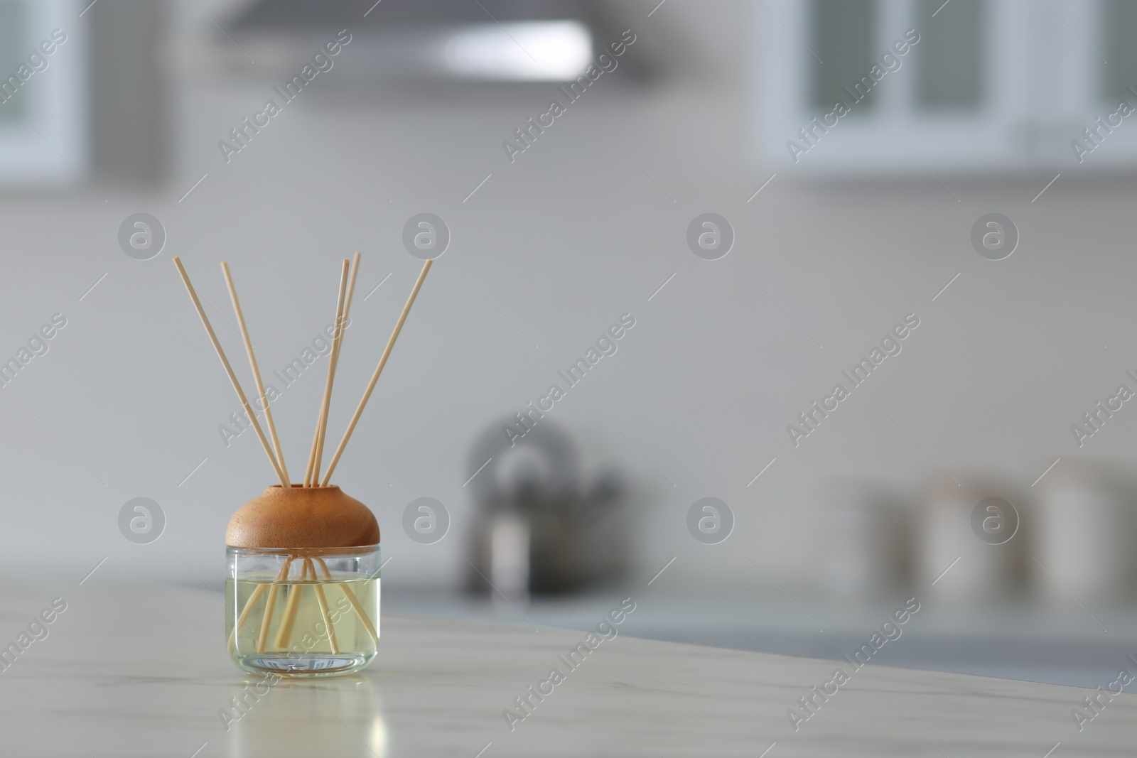 Photo of Aromatic reed air freshener on table indoors. Space for text