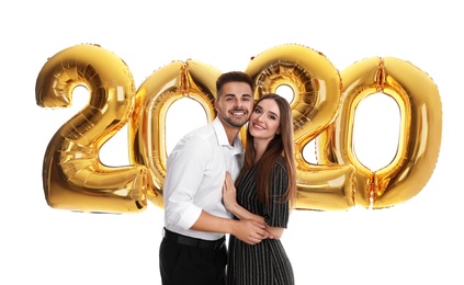 Photo of Happy young couple near golden 2020 balloons on white background. New Year celebration