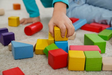 Photo of Cute little girl playing with colorful building blocks on floor, closeup