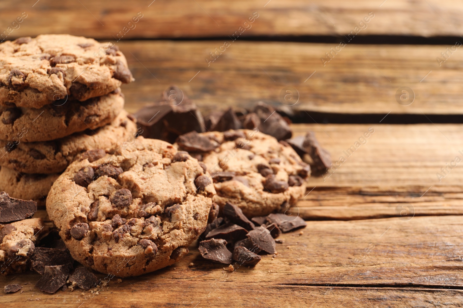 Photo of Many delicious chocolate chip cookies on wooden table. Space for text