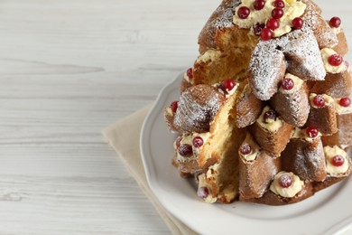 Photo of Delicious Pandoro Christmas tree cake with powdered sugar and berries on white wooden table, closeup. Space for text