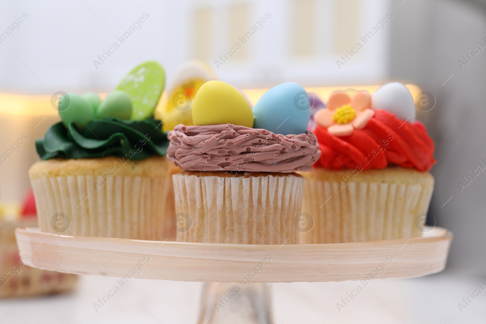 Photo of Tasty decorated Easter cupcakes on stand, closeup