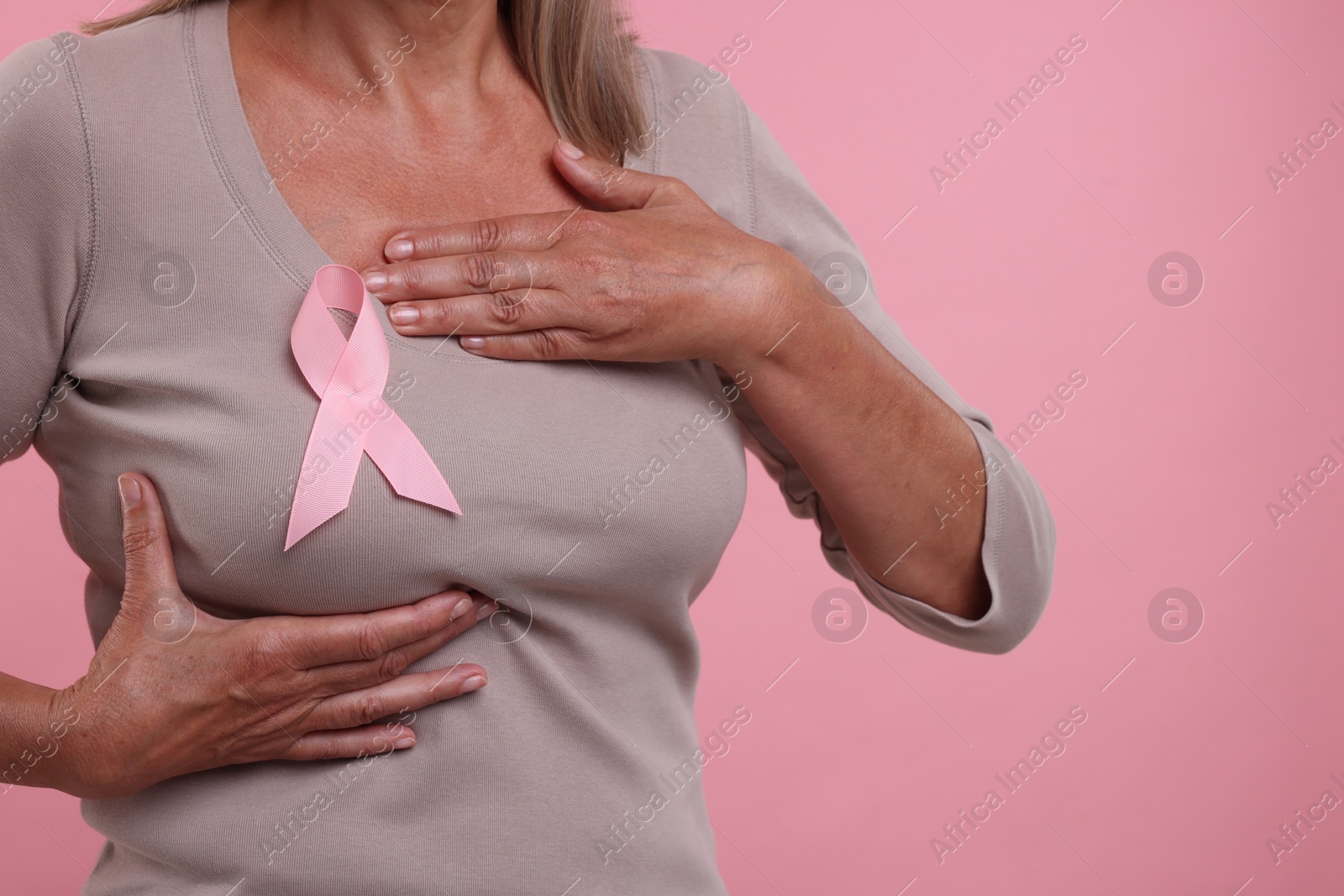 Photo of Woman with pink ribbon on color background, closeup. Breast cancer awareness