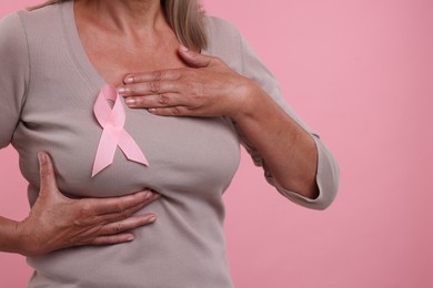 Photo of Woman with pink ribbon on color background, closeup. Breast cancer awareness