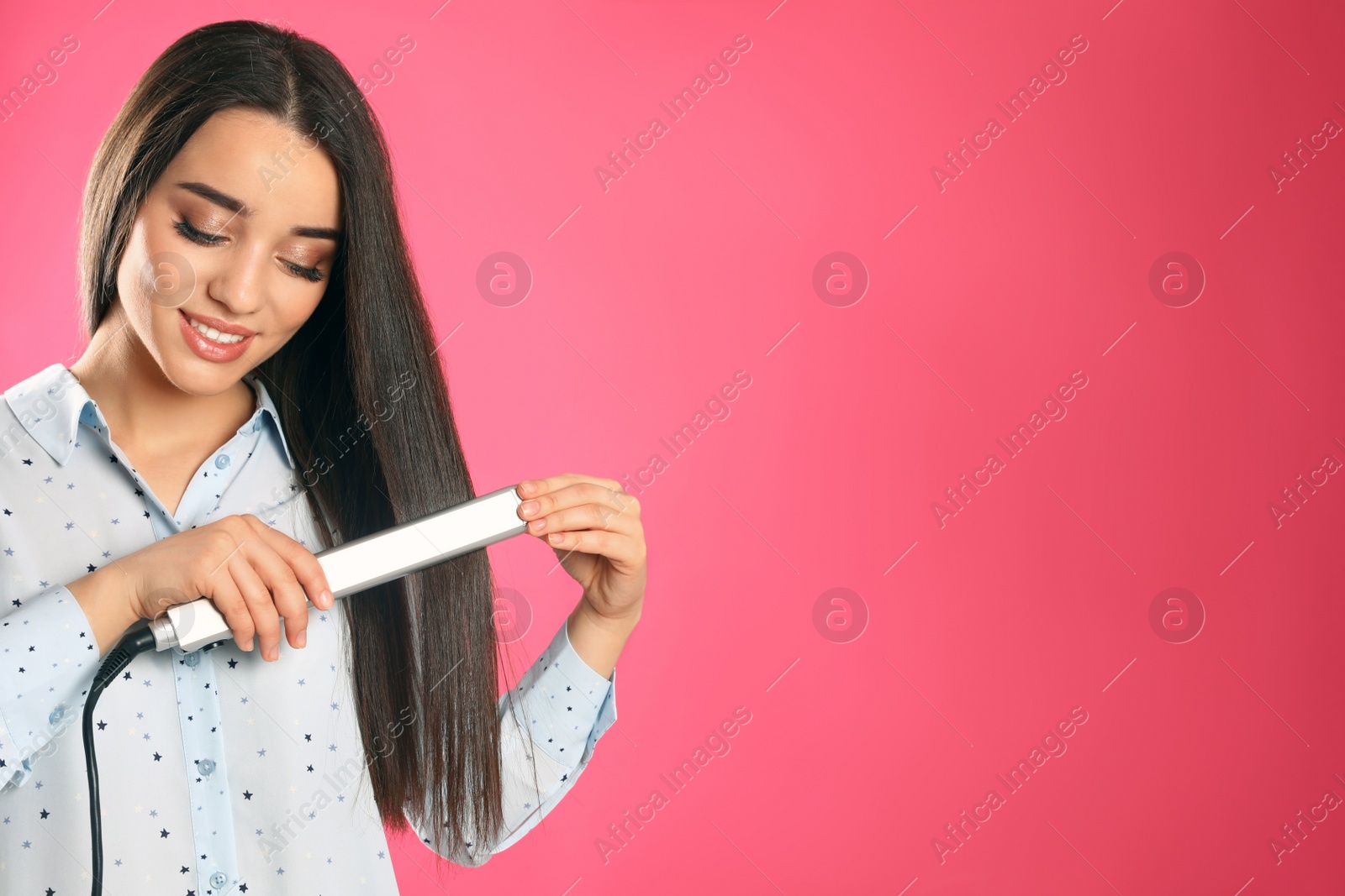 Photo of Happy woman using hair iron on color background. Space for text