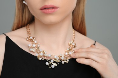 Photo of Woman with elegant necklace on gray background, closeup