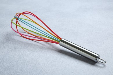 Photo of Bright whisk on gray table. Kitchen tool