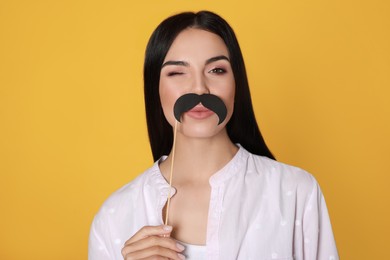 Funny woman with fake mustache on yellow background