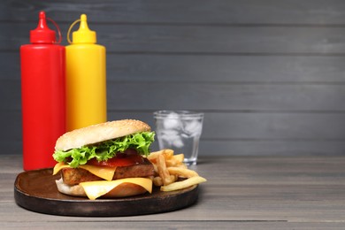 Photo of Delicious tofu burger served with french fries on grey wooden table. Space for text