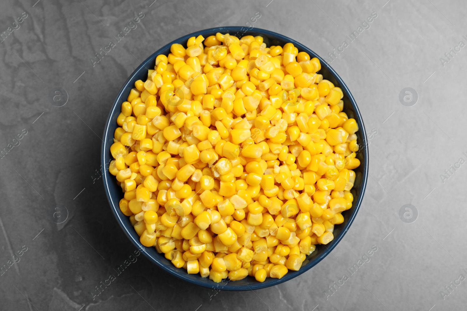 Photo of Delicious canned corn in bowl on grey table, top view