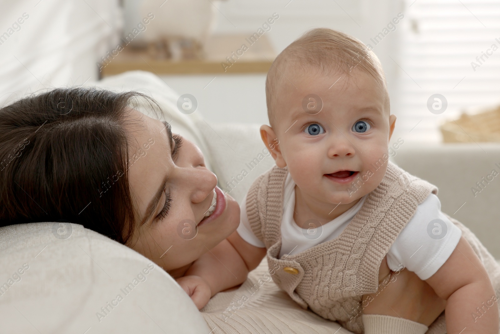 Photo of Happy young mother with her baby on sofa in living room