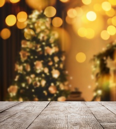 Image of Empty wooden surface and blurred view of Christmas tree in room, space for text. Interior design